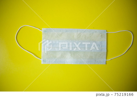 Protective medical mask on the table. The background is yellow with art paint. Lying carelessly 75219166