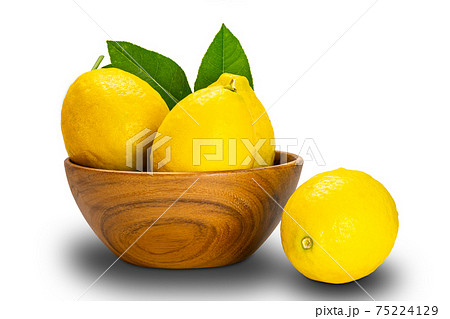 Ripe lemons with leaves in a wooden bowl on white background. 75224129