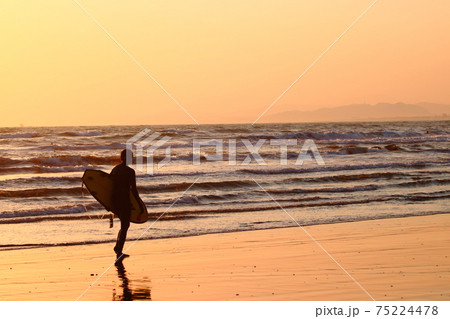 夕暮れの海岸線を歩くサーファー(女性) 夕暮れの海岸線を歩くサーファー(女性) 75224478