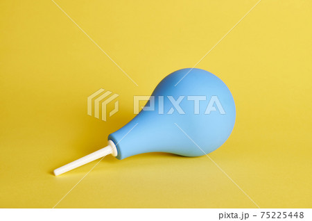 A blue medical rubber constipation enema on yellow background with copy space. Shot with light shadow. 75225448