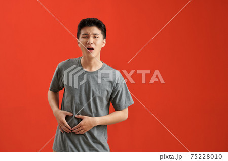 Young asian man wearing a white tshirt sick, suffering from stomachache, painful disease concept. 75228010