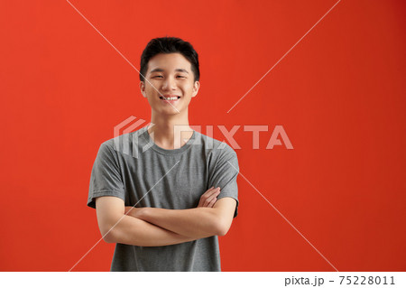 Portrait of Asian handsome man with arms crossed isolate on red background with copy space for text 75228011