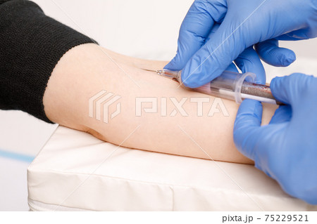 Nurse takes a blood sample from arm vein performing a venipuncture 75229521