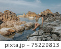 Beautiful woman walking on rock over sea 75229813