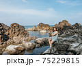 Beautiful woman walking on rock over sea 75229815