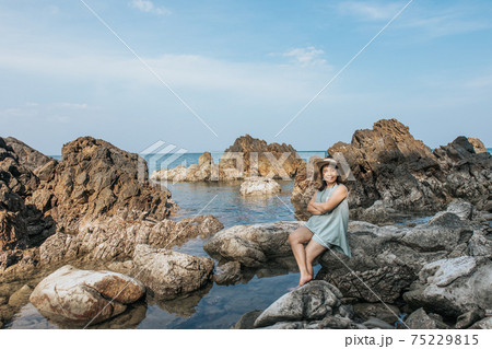 Beautiful woman walking on rock over sea Beautiful woman walking on rock over sea 75229815