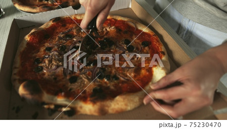 Delicious pizza being sliced up on the table Delicious pizza being sliced up on the table 75230470