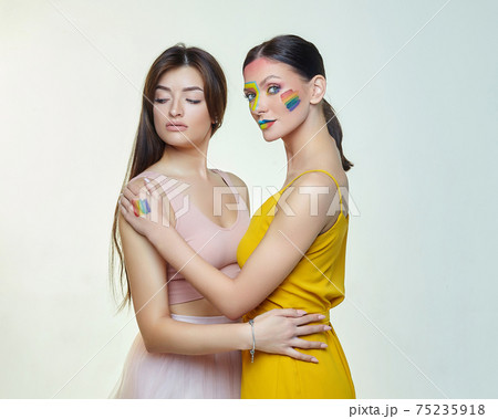 two young girls in the studio. one of them has a rainbow LGBT flag on her cheek two young girls in the studio. one of them has a rainbow LGBT flag on her cheek 75235918