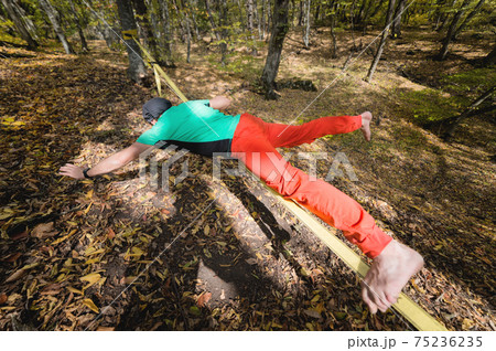 Portrait of a mature male highliner doing slackline balance training in the forest in autumn 75236235