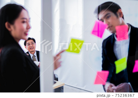 asia business man and woman pointing to paper post it on glass board explain document with manager in the office.businesswoman in meeting with colleagues, gesturing.Selective Focus asia business man and woman pointing to paper post it on glass board explain document with manager in the office.businesswoman in meeting with colleagues, gesturing.Selective Focus 75236367