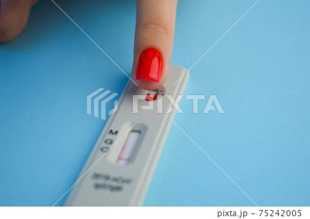 test for coronavirus on a blue background. a girl with a bright red manicure makes a blood test to determine the IgG and IgM class antibodies. health monitoring test for coronavirus on a blue background. a girl with a bright red manicure makes a blood test to determine the IgG and IgM class antibodies. health monitoring 75242005