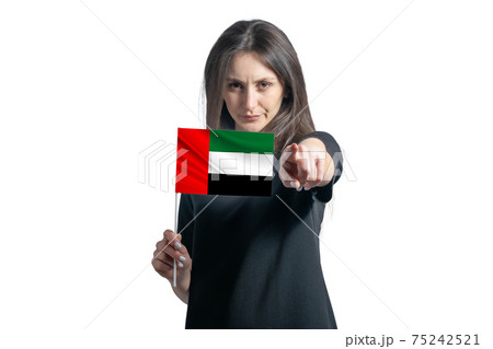 Happy young white woman holding flag of United Arab Emirates and points forward in front of him isolated on a white background 75242521