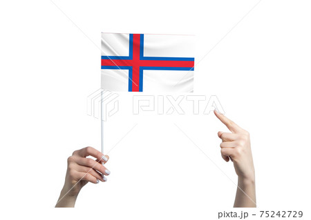 A beautiful female hand holds a Faroe Islands flag to which she shows the finger of her other hand, isolated on white background 75242729
