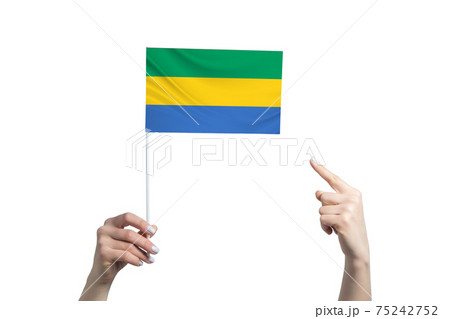 A beautiful female hand holds a Gabon flag to which she shows the finger of her other hand, isolated on white background 75242752