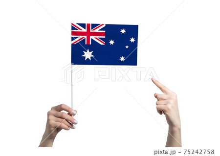 A beautiful female hand holds a Australia flag to which she shows the finger of her other hand, isolated on white background A beautiful female hand holds a Australia flag to which she shows the finger of her other hand, isolated on white background 75242758