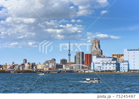 東京 築地 隅田川に運航する水上バスと背景に築地のビル群と東京スカイツリータワー の写真素材