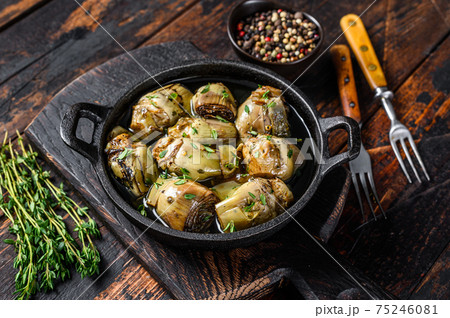 Marinated artichokes in olive oil in a pan. Dark wooden background. Top view Marinated artichokes in olive oil in a pan. Dark wooden background. Top view 75246081