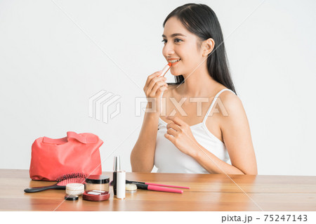 attractive beautiful mixed race asian woman applying lipstick on her lips 75247143