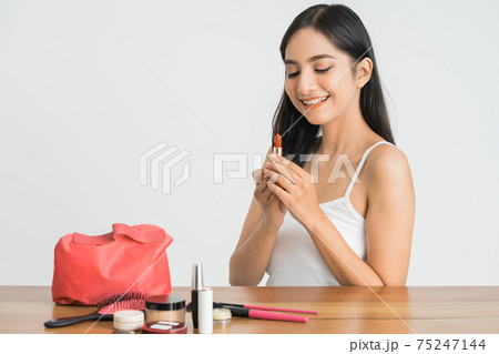 attractive beautiful mixed race asian woman applying lipstick on her lips 75247144