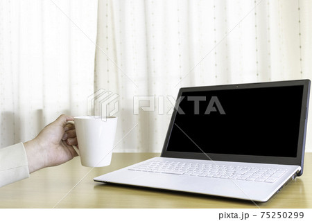 ノートパソコンにコーヒーカップを向ける男性 75250299