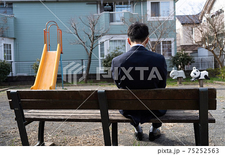 公園のベンチに座っているスーツを着た男性の写真素材