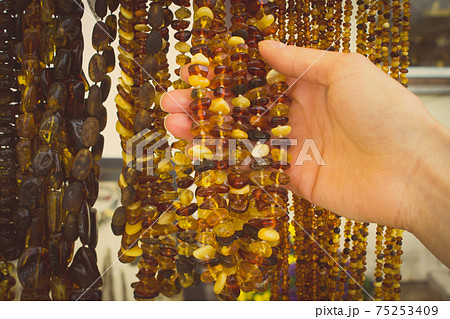 Vintage photo, Hand of woman with shiny womanly amber necklaces on stall 75253409