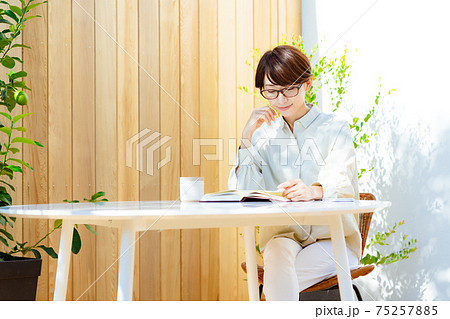 テラスで読書をする眼鏡をかけたミドルの女性 テラスで読書をする眼鏡をかけたミドルの女性 75257885