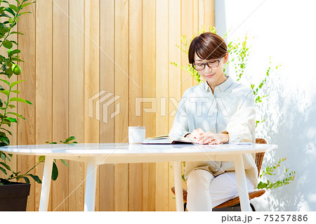 テラスで読書をする眼鏡をかけたミドルの女性 テラスで読書をする眼鏡をかけたミドルの女性 75257886