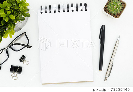 White office desk table with blank notebook page and supplies. Top view, flat lay. 75259449