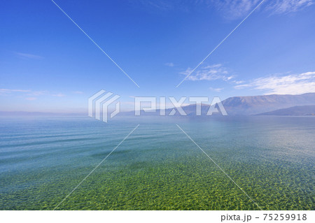 Amazing view on the green tree, mountains, sea with turquoise water and colorful blue sky at sunrise. Summer landscape in mountains on seashore. Amazing view on the green tree, mountains, sea with turquoise water and colorful blue sky at sunrise. Summer landscape in mountains on seashore. 75259918