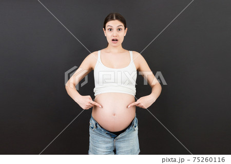 Picture of shocked or surprised pregnant lady standing over colored background. Looking at camera 75260116