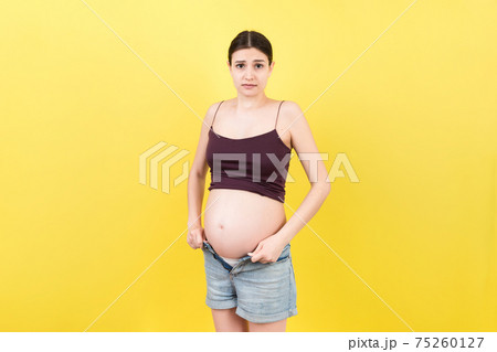 pregnant woman in unzipped jeans showing her naked belly at colorful background with copy space. Baby expecting concept 75260127