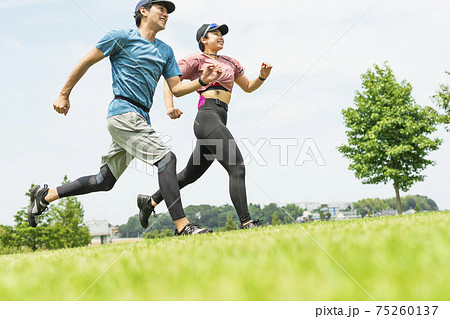 公園を走る男女の写真素材