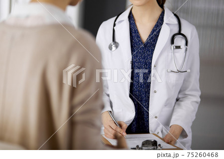 Doctor and patient discussing current health examination while sitting in clinic. Perfect medical service in hospital. Medicine concept 75260468