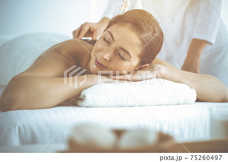 Beautiful brunette woman enjoying back massage with closed eyes. Spa and medicine concept Beautiful brunette woman enjoying back massage with closed eyes. Spa and medicine concept 75260497