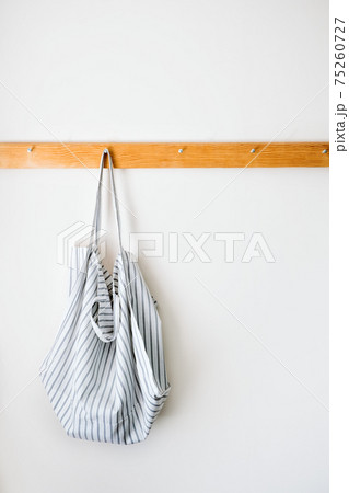 Minimalistic neutral tones mockup with organic cotton eco tote shopper bag on wooden hanger on a gray wall. Zero waste, Sustainable lifestyle, ecology concept Minimalistic neutral tones mockup with organic cotton eco tote shopper bag on wooden hanger on a gray wall. Zero waste, Sustainable lifestyle, ecology concept 75260727