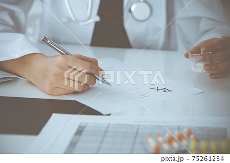 Unknown woman-doctor fills up prescription form. close-up. Panacea and life save, prescribe treatment, legal drug store. Medicine concept Unknown woman-doctor fills up prescription form. close-up. Panacea and life save, prescribe treatment, legal drug store. Medicine concept 75261234