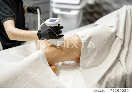 Doctor doing ultrasound liposuction procedure in medical clinic. Doctor doing ultrasound liposuction procedure in medical clinic. 75264029