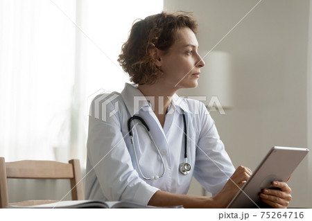 Pensive female doctor use tablet thinking of problem solution Pensive female doctor use tablet thinking of problem solution 75264716