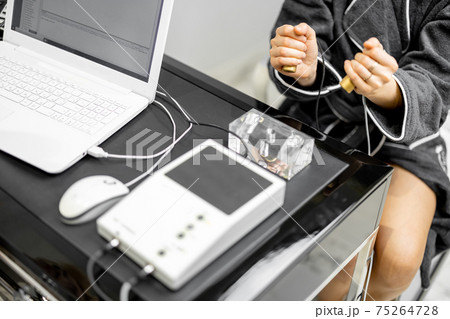 Woman takes hold of the brass handpieces of bioenergetic testing device 75264728
