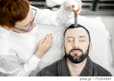Cosmetologist doing laser facelifting procedure in beauty clinic Cosmetologist doing laser facelifting procedure in beauty clinic 75264884