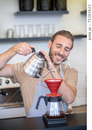 Smiling man pouring water into a pourover 75265622