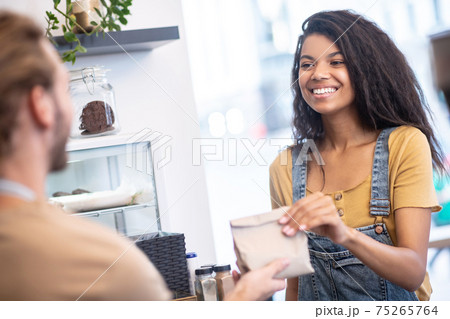 Woman taking paper bag from man behind counter 75265764
