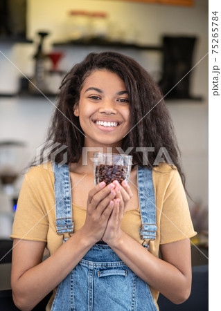 Shining woman with glass of coffee beans 75265784