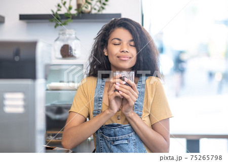 Woman with closed eyes with glass of coffee beans 75265798