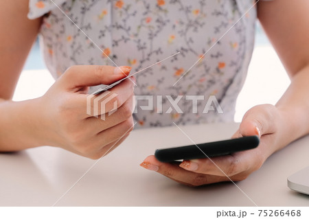 Close up hand of woman using smart phone and holding credit card Close up hand of woman using smart phone and holding credit card 75266468