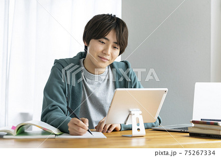 タブレットを見ながら勉強する若い男性　オンライン授業を受ける学生　イメージ 75267334