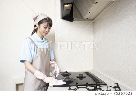 ガスレンジの清掃をするハウスクリーニングの女性作業員 75267623
