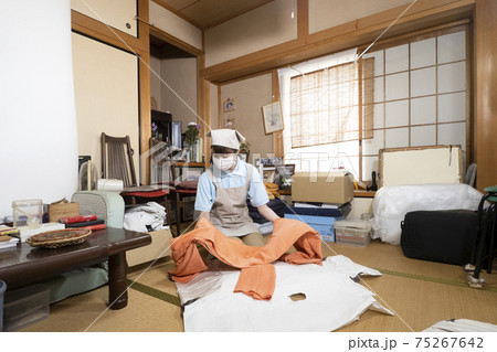 散らかった部屋を片付ける女性作業員 散らかった部屋を片付ける女性作業員 75267642