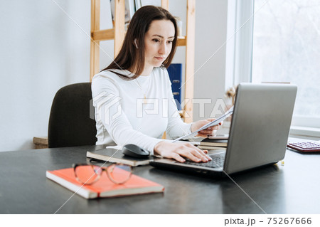 Remote Accounting Finance Jobs. Online Accounting Solution. Candid portrait of female accountant working with laptop, calculator and documents at home office Remote Accounting Finance Jobs. Online Accounting Solution. Candid portrait of female accountant working with laptop, calculator and documents at home office 75267666
